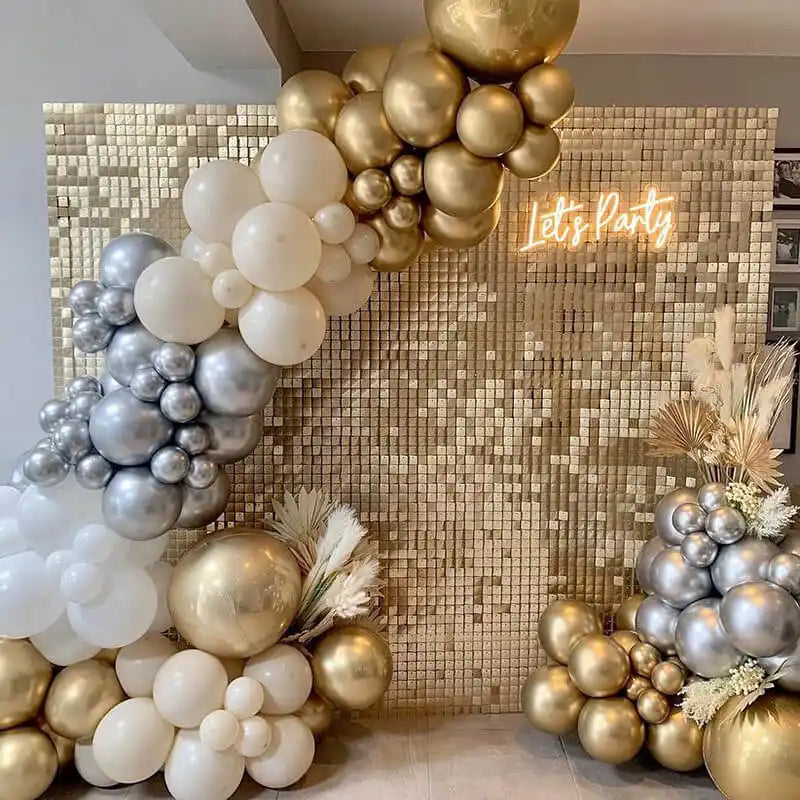 Balloon arch made of white, gold, and silver balloons with dried palm fronds accents.